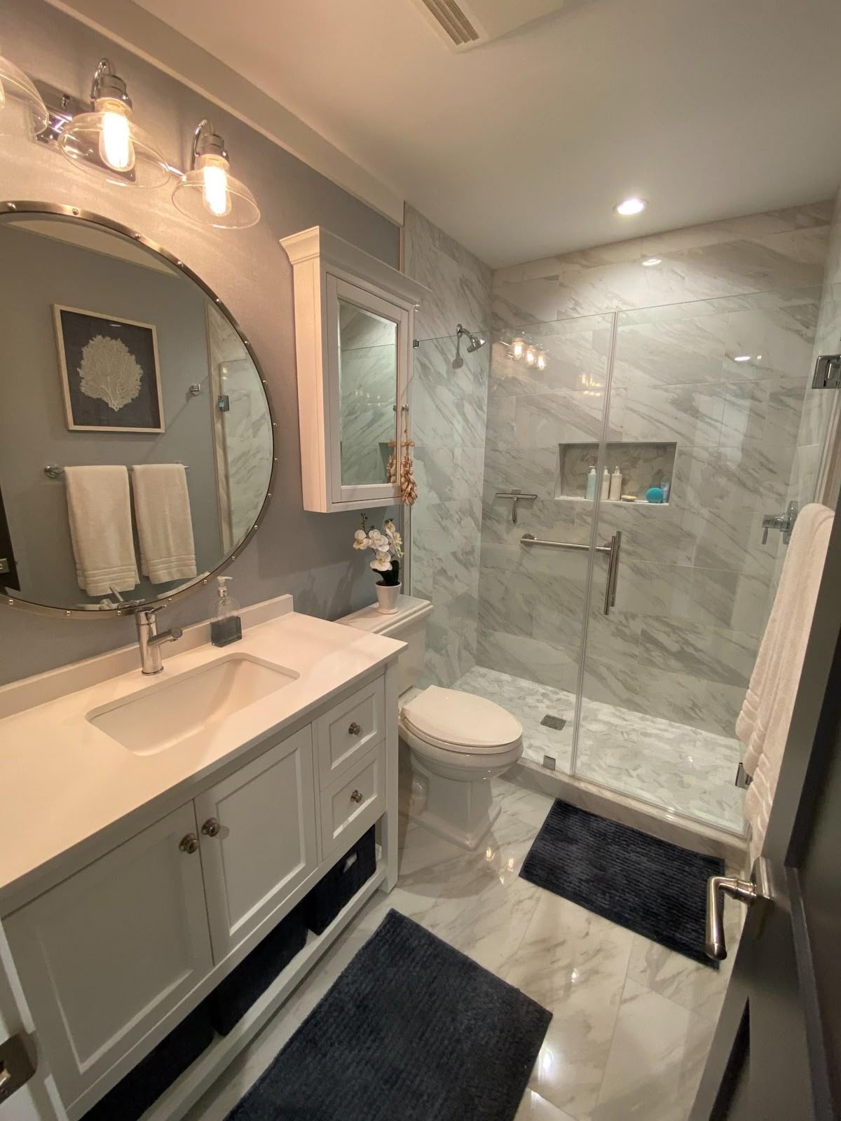 Marble-look tile walk-in shower with glass enclosure and built-in niche