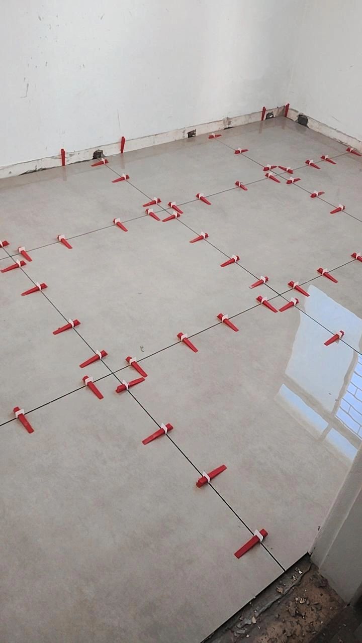 Large-format tile being installed with a leveling system for a perfectly flat floor